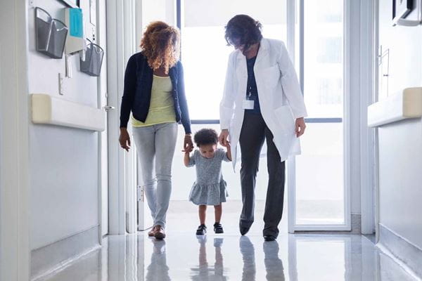 Mother, daughter and doctor walking down a hallway