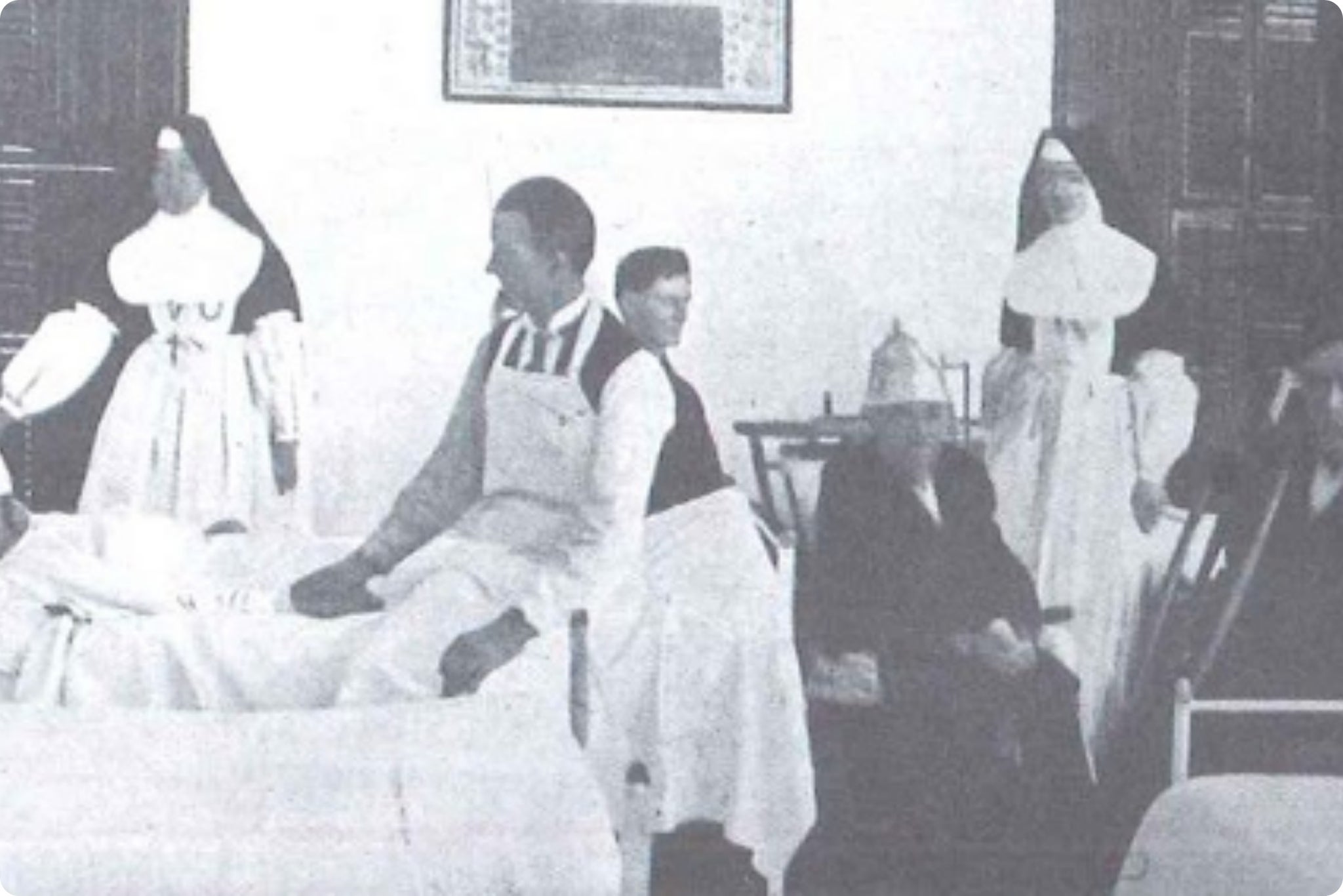 Historic black and white photograph of Catholic sisters and medical staff tending to patients in a hospital ward.