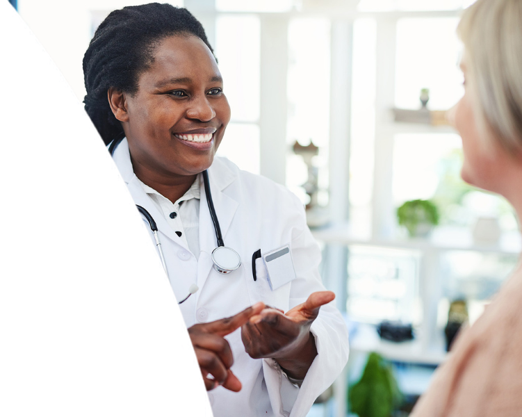 A smiling female doctor speaking with a patient while gesturing with her hands.
