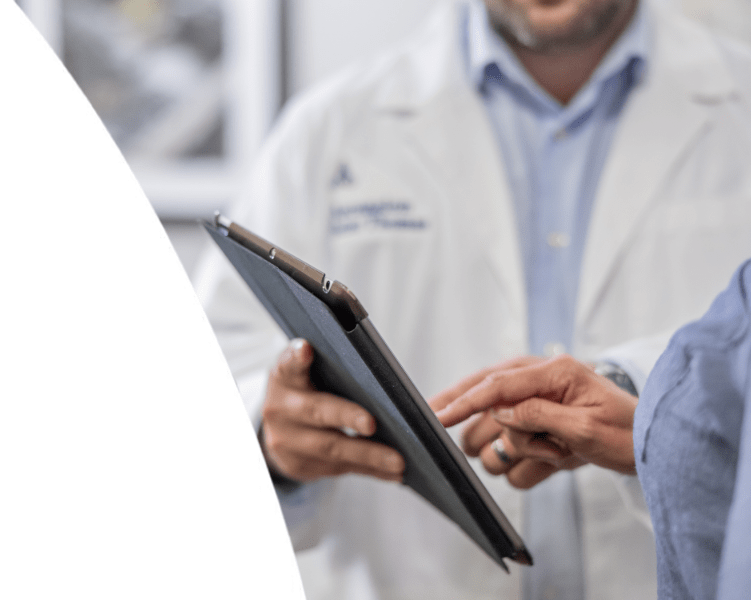 A doctor in a white coat showing information on a digital tablet to a patient.