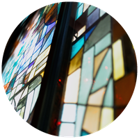 Angled close-up of colorful mosaic stained glass windows illuminated by soft light.