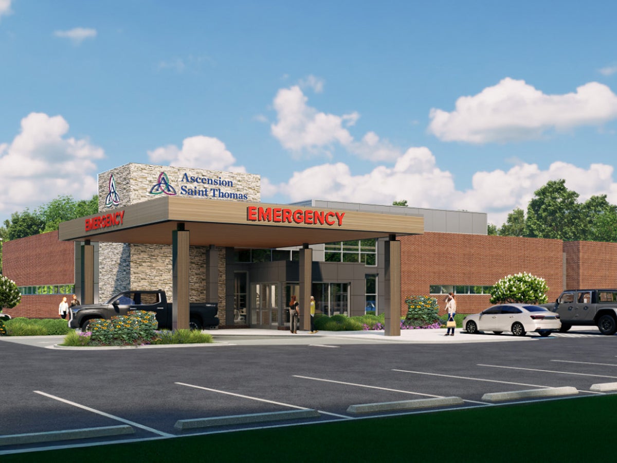 Proposed rendering of the Ascension Saint Thomas Freestanding Emergency Department in Fairview, Tennessee, showing a one-story brick and stone building with a covered ambulance and patient drop-off entrance marked “Emergency.” The 11,345-square-foot facility will provide 24/7 emergency care with 10 treatment rooms, triage and trauma rooms, on-site imaging and laboratory services, and is planned for construction near Highway 96 and Audubon Cove beginning in 2026, pending state approval.