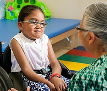 Adult speaking with a child in wheelchair