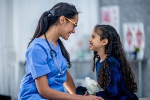 Health professional and a young girl smiling at each other